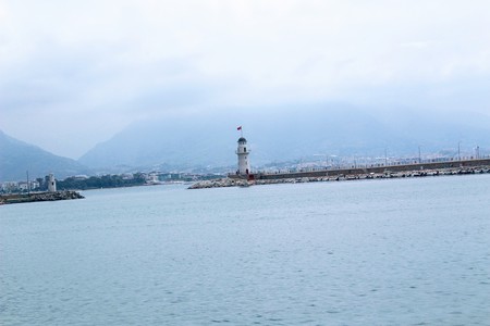 White lighthouse at the end of the berth in the city harbor (Alanya, Turkey).の写真素材