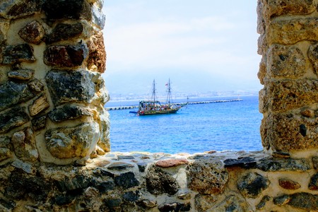 View of a pleasure sailing ship for a sea excursion through the loophole of the fortress wall (Antalya, Turkey).のeditorial素材
