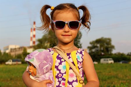 Russia, Suvorov, 08.2017: Portrait of a girl in sunglasses which play with a doll.のeditorial素材
