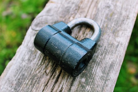 Black padlock lying on a wooden Board.の写真素材