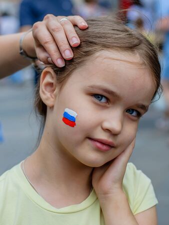Moscow, Russia - July 7, 2018: young european girl with russian tricolor on cheek, patriotic face painting, fans bodyartのeditorial素材