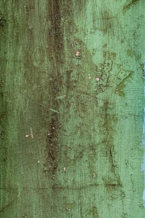 Dirty texture of plaster and green paint, shabby aged surface, remnants of peeling cracked stucco, grunge uneven wallの写真素材