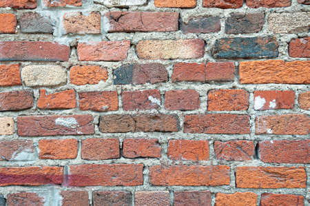 Old weathered red brick wall for texture or background, classic rough aged brickwork, vintage masonry with cement mortarの写真素材