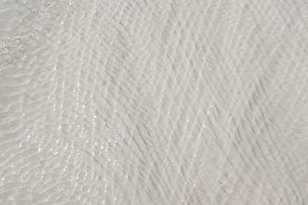 background of white travertine surface covered with flowing clear water with waves