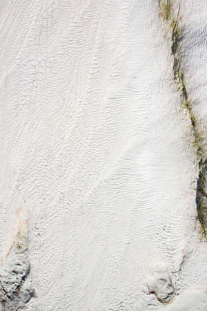 background of white travertine with relief and ribbed surface, green and yellow cracks from algaeの写真素材