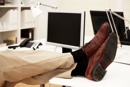 Feet of a businessman on the table in his officeの写真素材