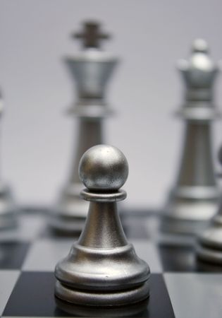 White silver chess pawn in front of king and queen. Pawn is ready to fight. White background.の写真素材
