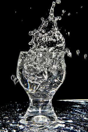 Ice splashing into a glass on white on black backgroundの写真素材