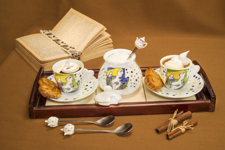 coffeetable coffee and milk cream with sugar cookies and a book on a brown backgroundの写真素材