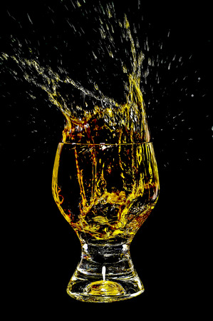 Ice splashing into a glass in black on yellow background 1の写真素材