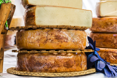 hand made cheeses stacked on wood exposedの写真素材