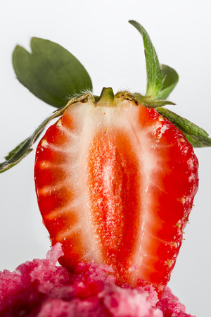 half strawberry on strawberry ice cream on a white backgroundの写真素材