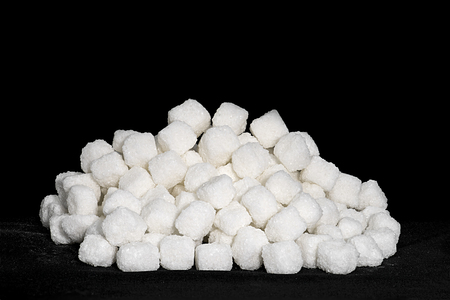 white cane sugar cubes stacked on a black backgroundの写真素材