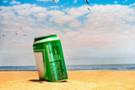 cold can of beer on the beach with seagulls flying over a blue skyの写真素材