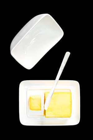 open butter dish with knife and butter on black backgroundの写真素材