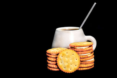 lemon-filled biscuits with a rustic ceramic cup behind on a black backgroundの写真素材