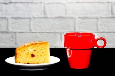 portion of homemade cake with a red cup of coffee on white backgroundの写真素材
