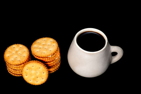 white plate with lemon cookies with cup of coffee seen from above on black backgroundの写真素材
