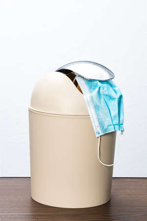 anti covid mask thrown in a trash can on a white background