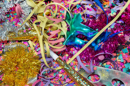 carnival bugle and blue carnival mask over confetti and multi-colored streamers on black backgroundの写真素材