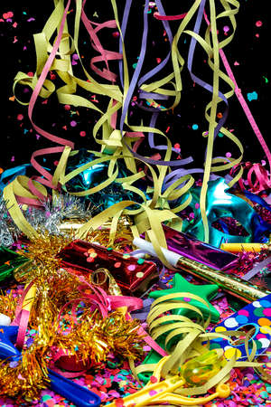 carnival bugle and blue carnival mask over confetti and multi-colored streamers on black backgroundの写真素材