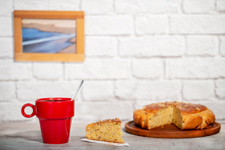 red cup of coffee with handmade sponge cake on a rustic tableの写真素材