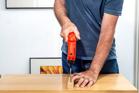 Man placing a screw with an electric screwdriver on a white backgroundの写真素材