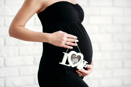 Pregnant woman is holding ultrasound scan on her belly.