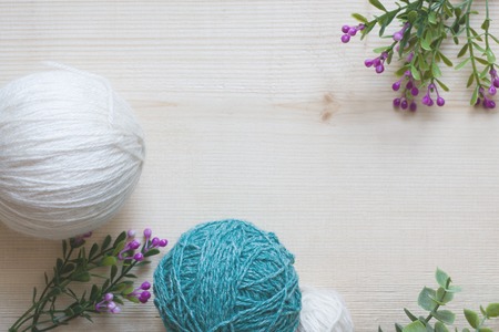 Yarn for knitting. Balls of yarn and flowers on a wooden background. Yarn for needlework. Flat lay, copy space, top view.の写真素材
