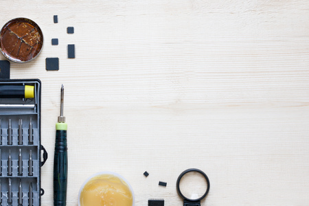 Repairman workplace with phone and special tools. Tool kit: multimeter, magnifying glass, soldering iron, rosin, tin, tweezers, screwdrivers, blades, tin pump. Electronics repair service. Place for your text, copy spase mockupの写真素材