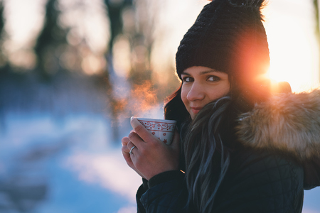 Young woman drinking hot tea winter snow outdoorの写真素材