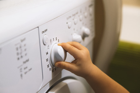 Child hand on the washing machine button