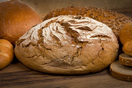 Breads with slices on wooden background