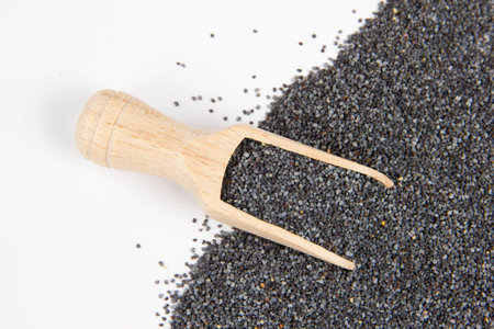 Pile of poppy seeds with wooden scoop isolated on whiteの写真素材