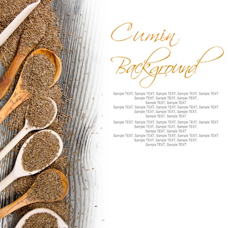 Photo of spoons with cumin seeds on wooden board with white space for text