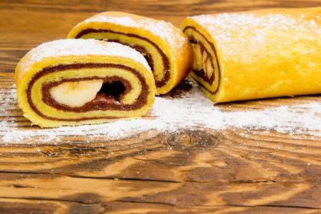 Photo of sliced roll cake on wooden board with white space for text