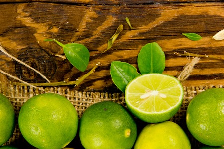 Photo of limes, slice and leaves on wooden boardの写真素材
