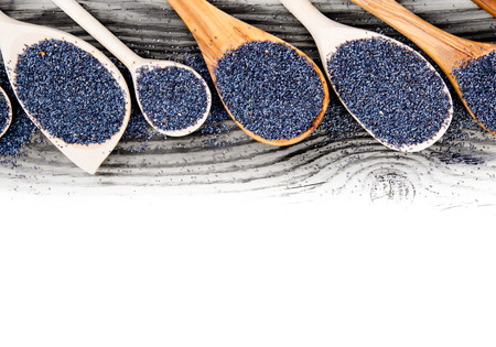 Photo of spoons with poppy seeds on wooden board with white space for textの写真素材