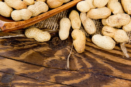 Photo of peanuts in saucer on wooden board