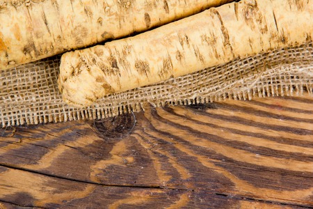 Photo of horseradish root on burlap and wooden boardの写真素材
