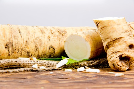 horseradish root with slice on burlap and wooden boardの写真素材