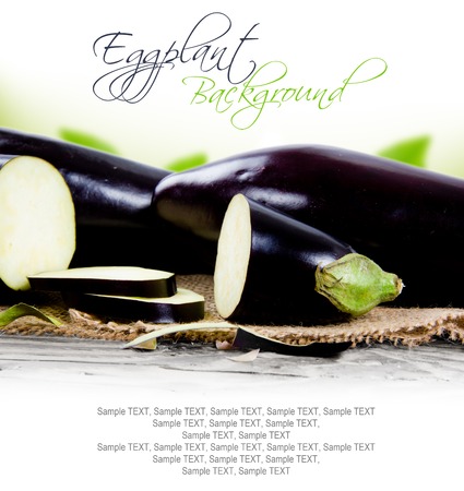 Photo of eggplants with slices on burlap and wooden board with white spaceの写真素材