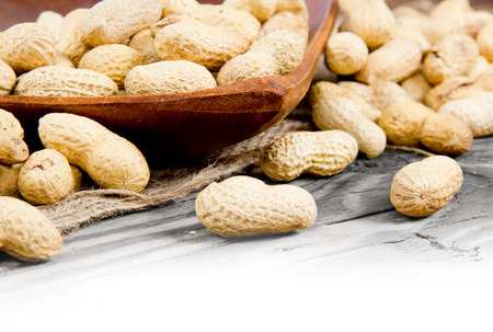 Photo of peanuts in saucer on wooden board with white space