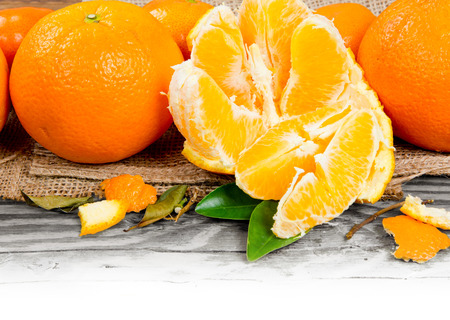 Photo of oranges with slices and leaves on wooden board with white space
