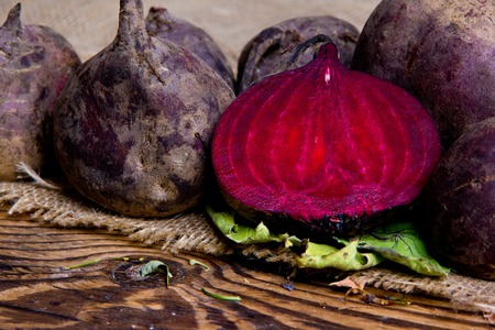 Photo of beetroots with leaves on burlap and wooden deskの写真素材