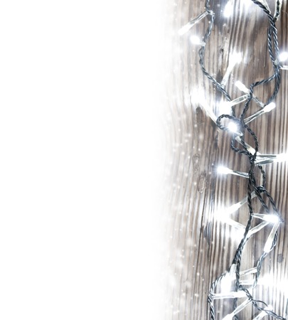 Photo of wooden board lit by Christmas light chain covered with snow; white space for textの写真素材