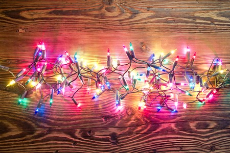 Photo of wooden board lit by Christmas light chain covered with snowの写真素材