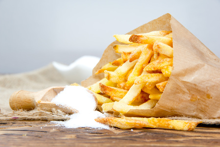 Photo of french fries with salt on wooden surface