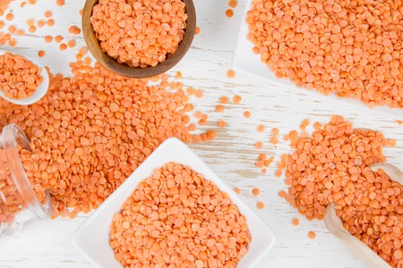 Photo of bowls full of lentil seeds on white wooden surface
