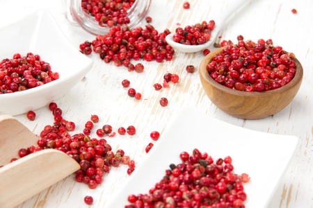 Photo of bowls full of red pepper seeds and powder on white wooden surface